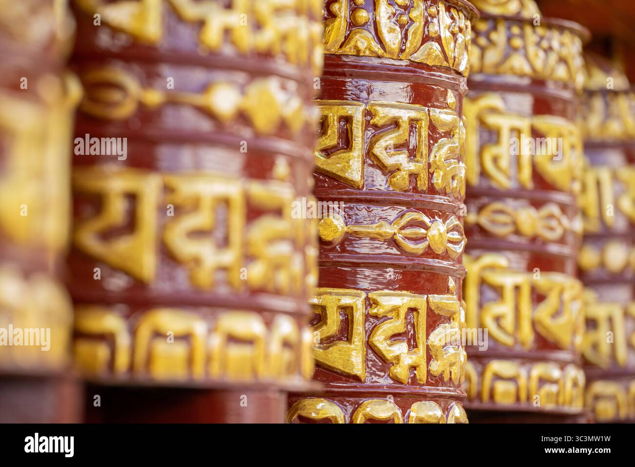 Immagine dettagliata delle tradizionali ruote di preghiera tibetane nella regione dell'Everest in Nepal, che mostra intricati motivi dorati e simboli su strutturu in legno Foto Stock