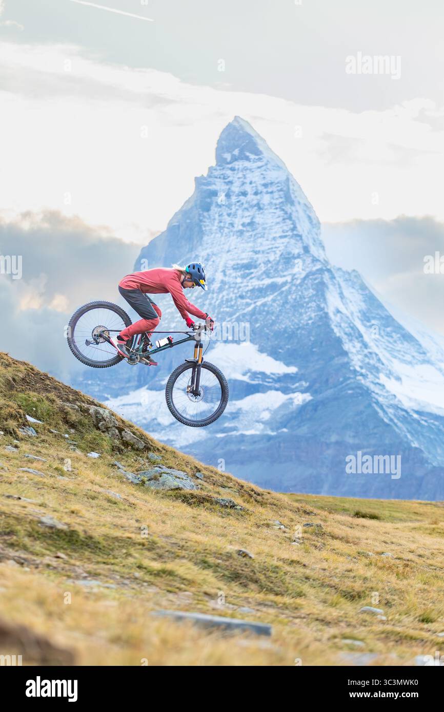 Un mountain bike percorre una ripida discesa nelle Alpi, con l'iconica vetta del Cervino sullo sfondo. La scena mostra gli sport estremi A. Foto Stock