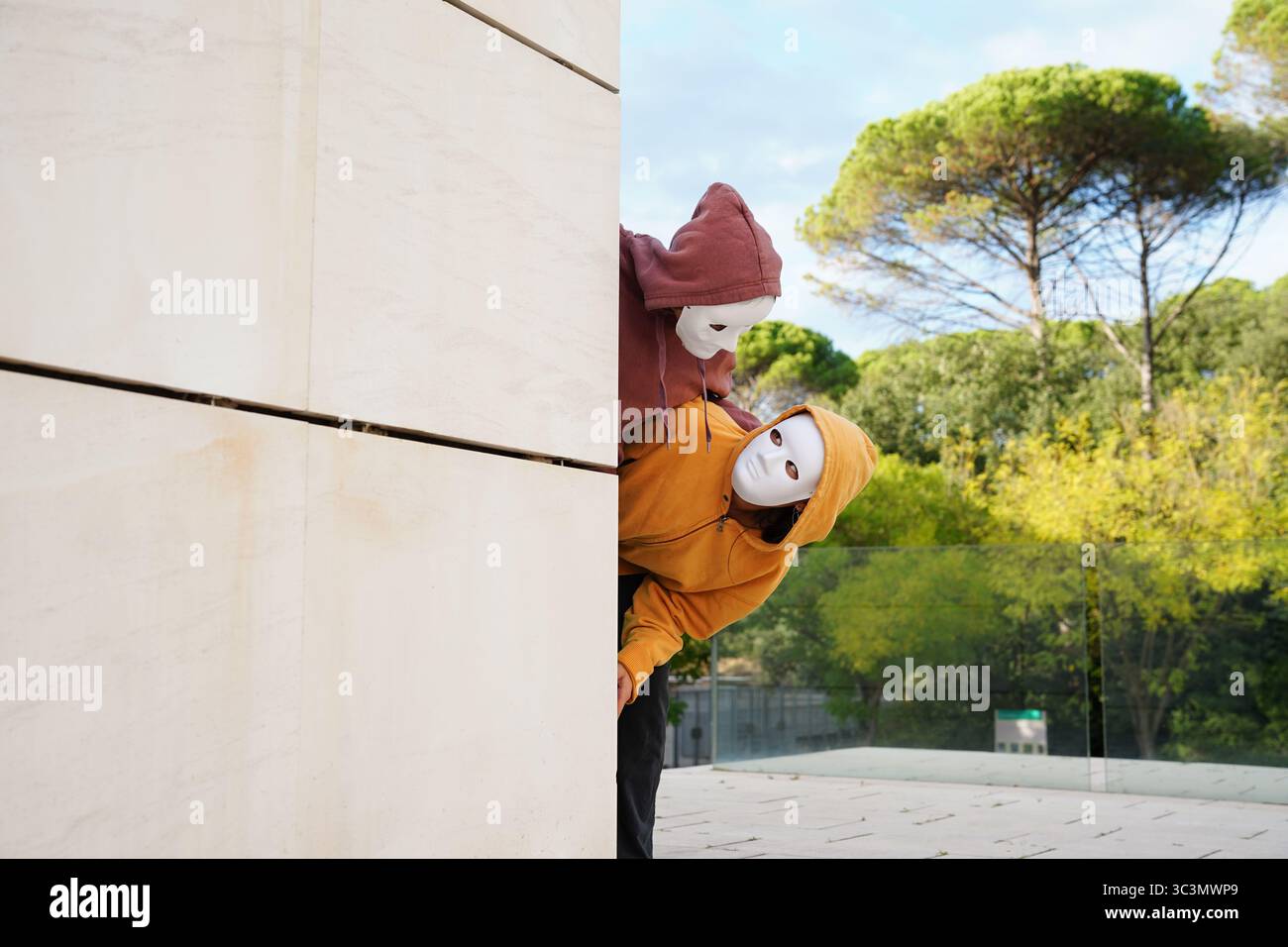 Gli adolescenti indossano maschere espressive mentre si godono una divertente lezione di teatro all'aperto. Si impegnano in attività creative, esplorando le espressioni teatrali Foto Stock