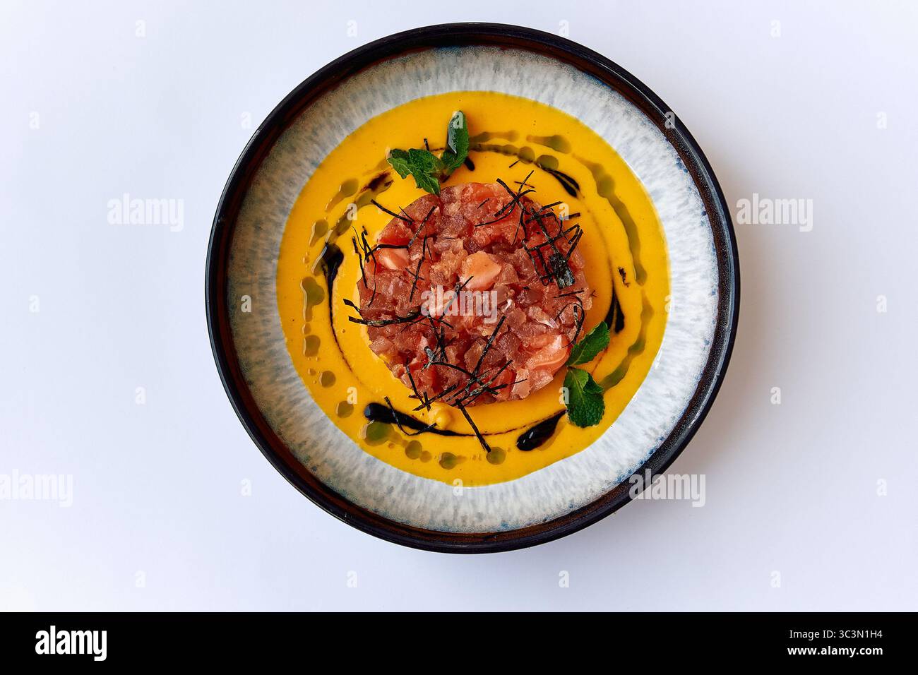 Un piatto gourmet caratterizzato da succulenta carne lavorata alla perfezione con salsa vibrante e decorazioni commestibili per una squisita esperienza culinaria Foto Stock