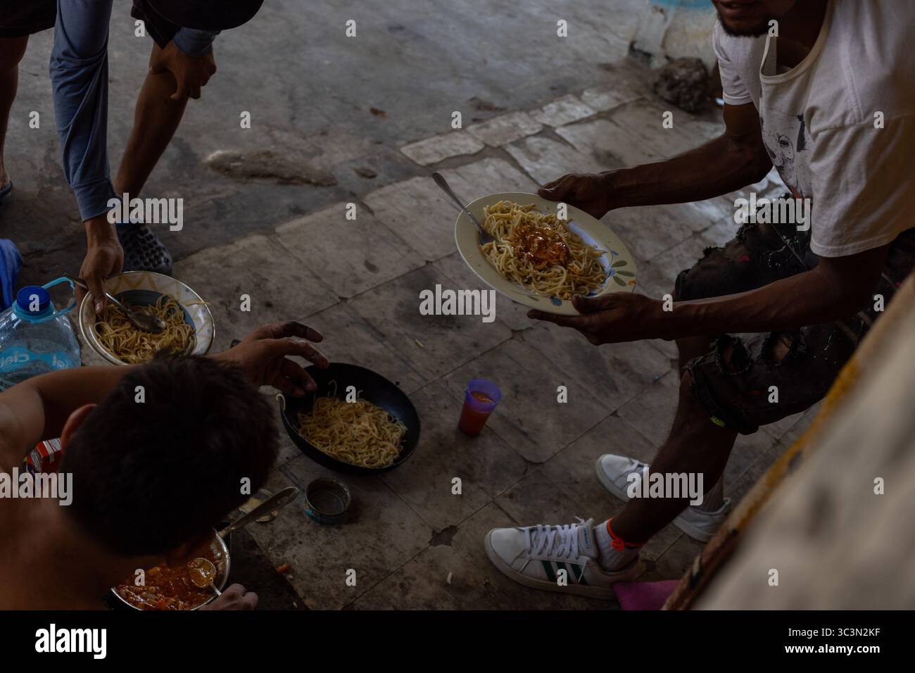 I migranti condividono un pasto, legandosi a Ciudad Juarez. Foto Stock