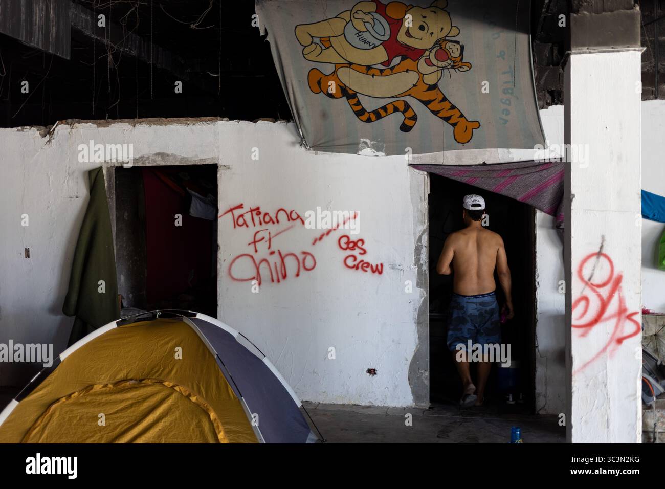 Un uomo in un rifugio improvvisato a Ciudad Juarez, che raffigura le dure realtà dei migranti. Foto Stock