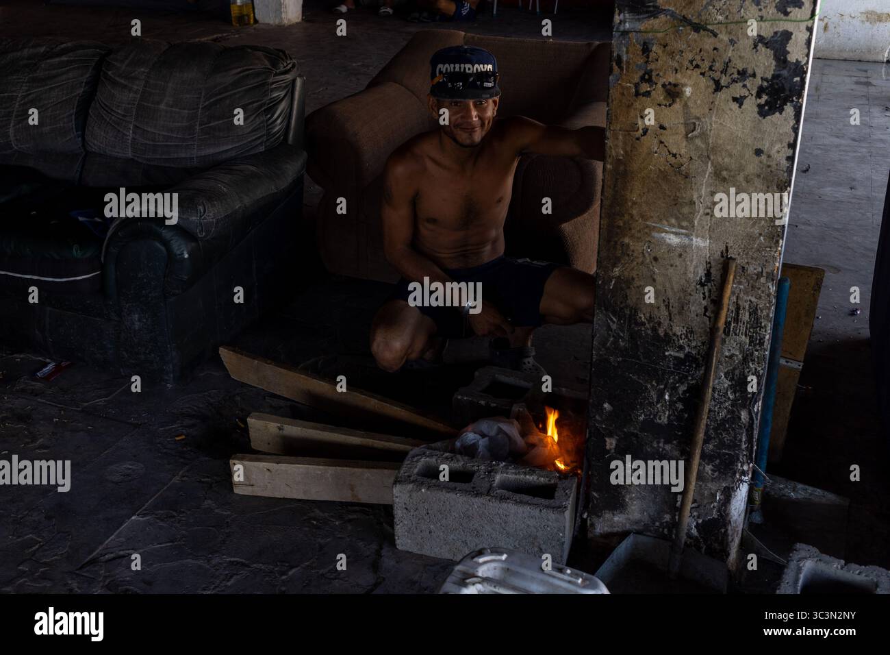 L'uomo prepara il pasto in una cucina improvvisata in mezzo alle lotte migratorie a Ciudad Juarez. Foto Stock
