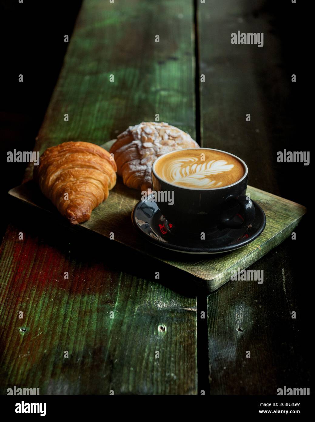 Croissant e tazza di caffè nero su sfondo nero. Messa a fuoco selettiva Foto Stock
