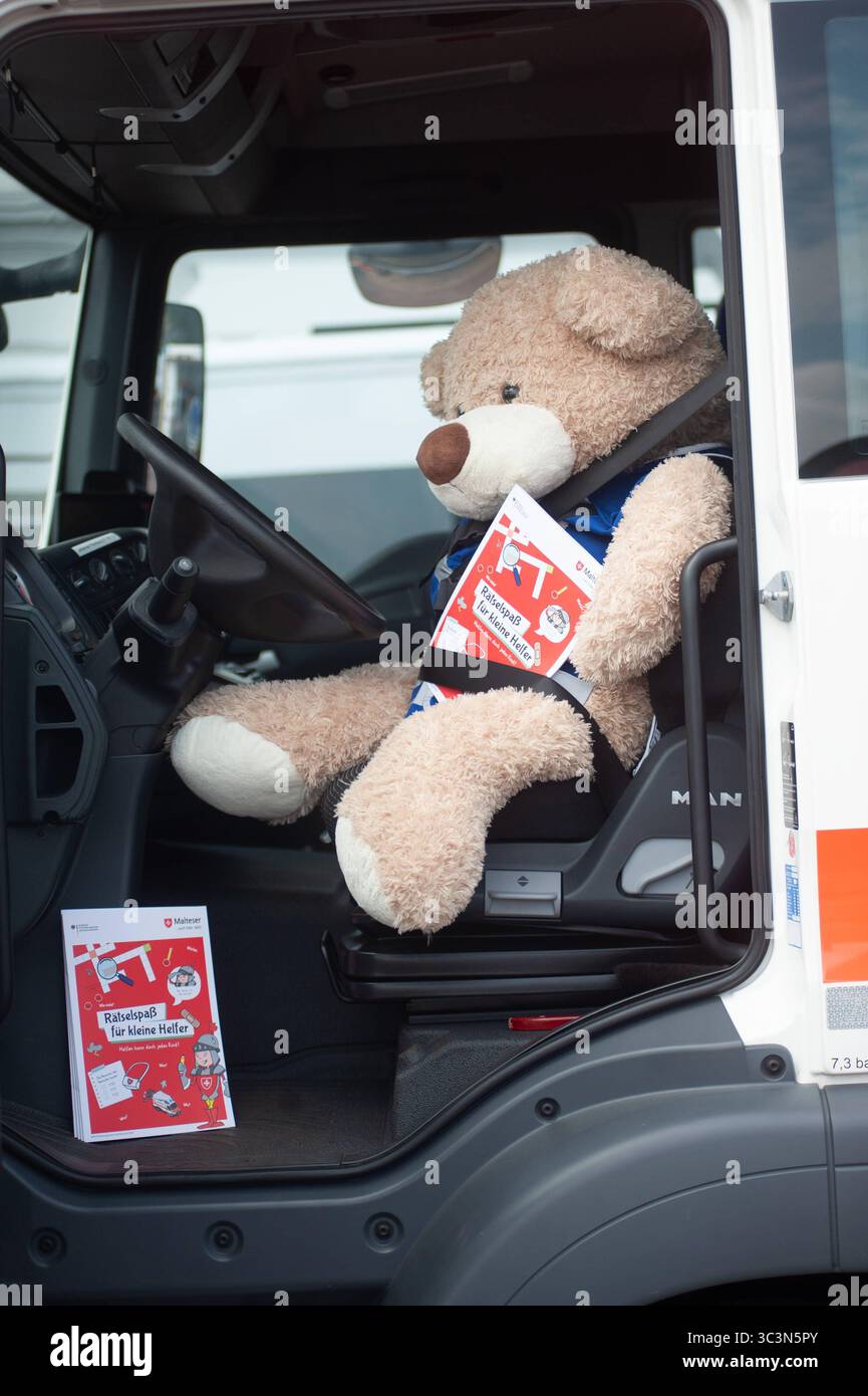 Flensburg, Schleswig-Holstein Flensburger Blaulichttag. DAS Bild zeigt ein sehr Großes Stofftier, einen hellbraunen Teddybär, der angeschnallt auf dem Fahrersitz eines LKW sitzt. Der Teddybär hält ein Heft mit rotem Titelblatt in den Pfoten, auf dem Rätselspaß für kleine Helfer steht. Die Fahrertür des Lkws steht offen, das Innere des Fahrerhauses ist gut sichtbar. Auf dem Trittbrett vor dem Sitz liegt ein weiteres Exemplar des gleichen Hefts. Die Szene wirkt humorvoll und kindgerecht, und macht im Rahmen der Information- und Kinderaktion, auf Verkehrssicherheit und das Thema Toter Winkel auf Foto Stock