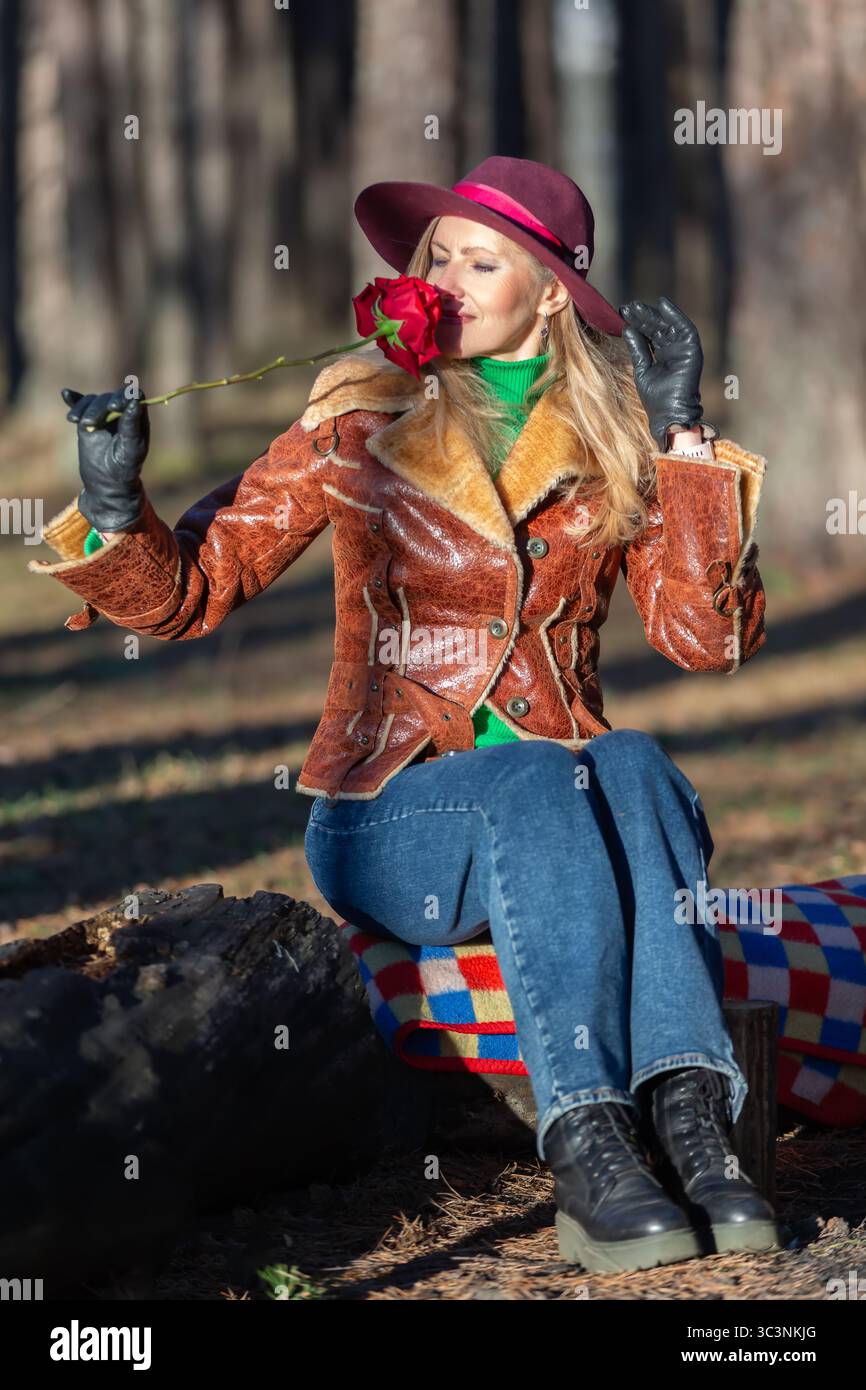 Una donna nella foresta ammira una rosa. Foto Stock