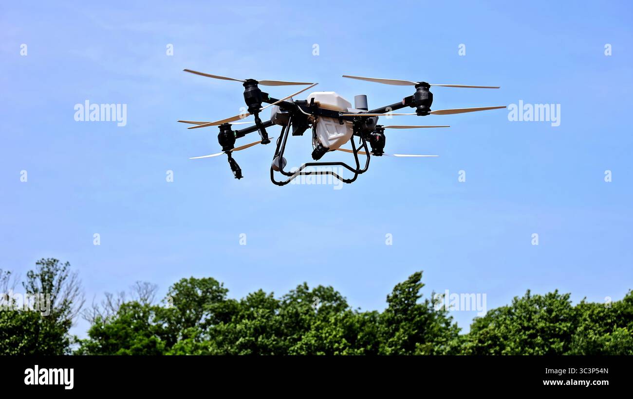 Drone agricolo che vola sul campo per il monitoraggio del raccolto. Drone agricolo ad alta tecnologia in volo contro il cielo blu, utilizzato per l'agricoltura di precisione, il raccolto Foto Stock