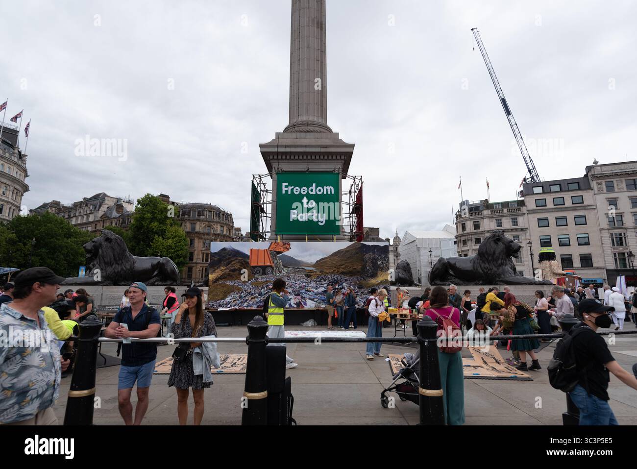 Londra, Regno Unito. 26 luglio 2025. Un grande banner verde con la scritta "Freedom to Party" è appeso alla colonna di Nelson mentre Trafalgar Square è decorata con opere d'arte organizzate da Jeremy Deller come parte delle celebrazioni del bicentenario della National Gallery. In primo piano viene mostrata un'enorme immagine di un paesaggio rovinato dai rifiuti umani. Crediti: Ron Fassbender/Alamy Live News Foto Stock Londra, Regno Unito. 26 luglio 2025. Un grande banner verde con la scritta "Freedom to Party" è appeso alla colonna di Nelson mentre Trafalgar Square è decorata con opere d'arte organizzate da Jeremy Deller come parte delle celebrazioni del bicentenario della National Gallery. In primo piano viene mostrata un'enorme immagine di un paesaggio rovinato dai rifiuti umani. Crediti: Ron Fassbender/Alamy Live News Foto Stock