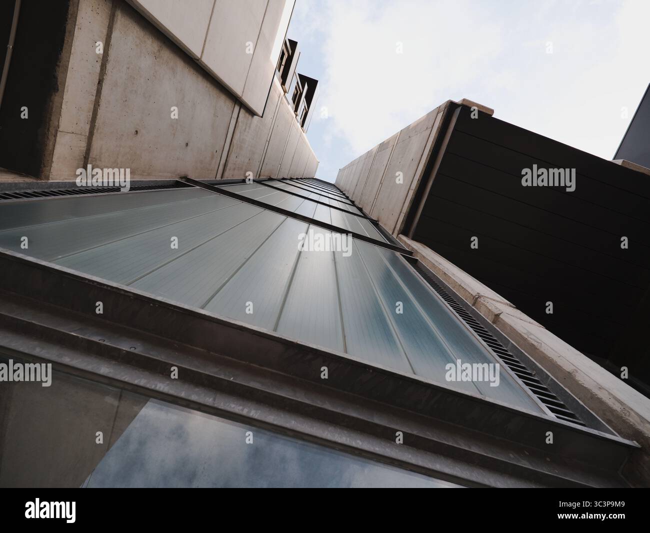 Vista verso l'alto della facciata di un edificio residenziale caratterizzato da elementi architettonici moderni. Pareti in cemento e traverse metalliche incorniciano la struttura, con Foto Stock