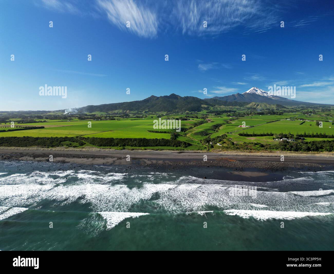 Vista aerea delle onde dell'Oceano Pacifico che colpiscono la costa di Capo Egmont vicino a Pitone, nuova Zelanda con il Monte Taranaki Foto Stock
