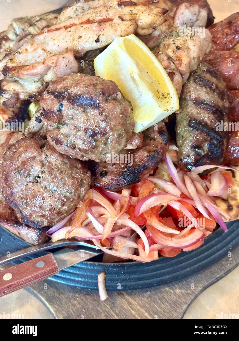 Primo piano di un tradizionale piatto di carne alla griglia greco servito ad Atene, Grecia, con souvlaki, polpette, salsicce, pollo alla griglia e un lato di - Immagine stock catturata con smartphone