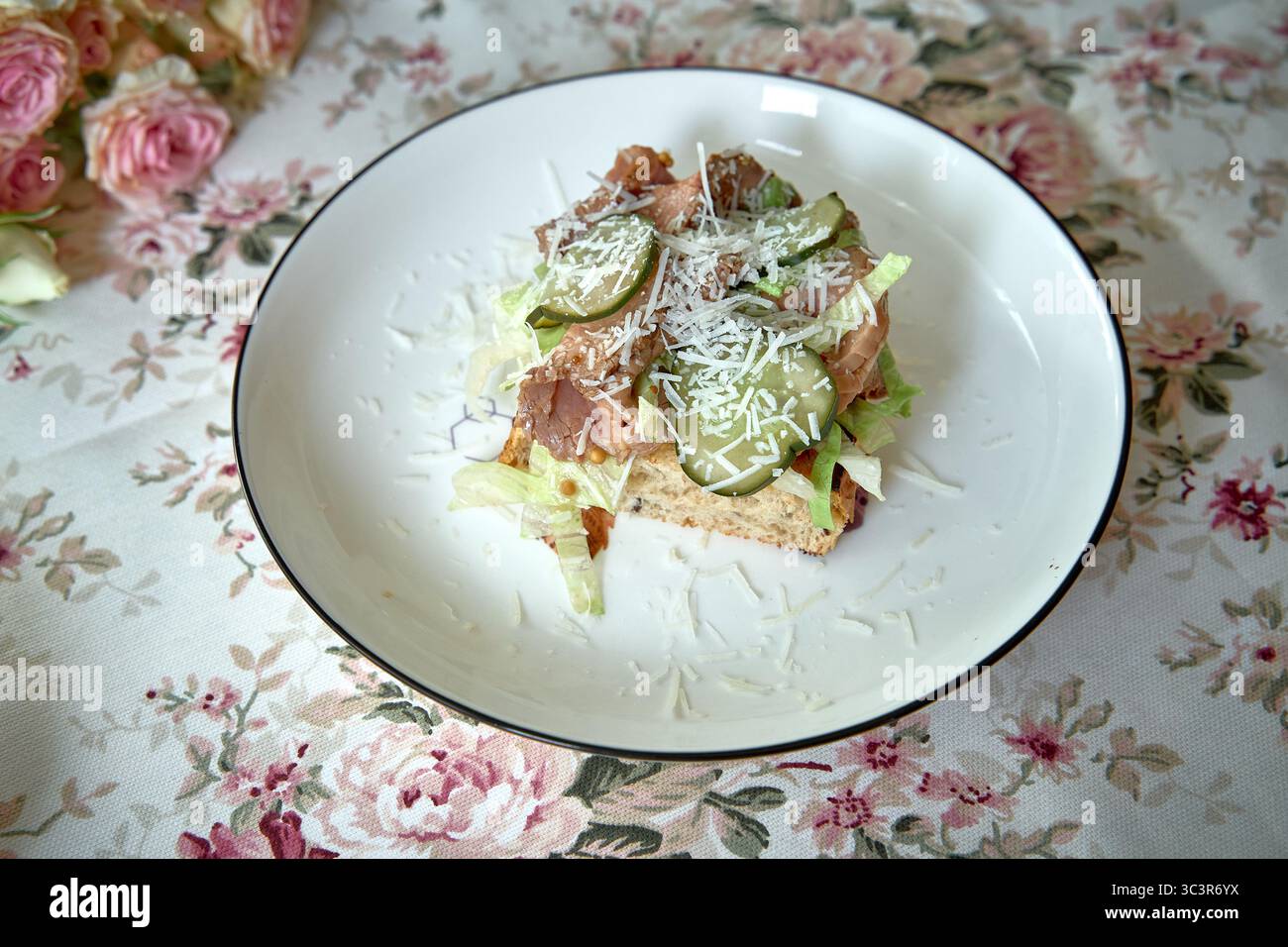 Un delizioso piatto di insalate con lattuga fresca, proteine magre, crocchette e formaggio grattugiato su una base di pane leggermente tostata, perfetto per un'eatina sana Foto Stock