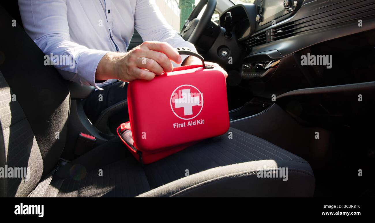 Il medico maschile ripone i materiali di pronto soccorso nel vano portaoggetti per auto Foto Stock