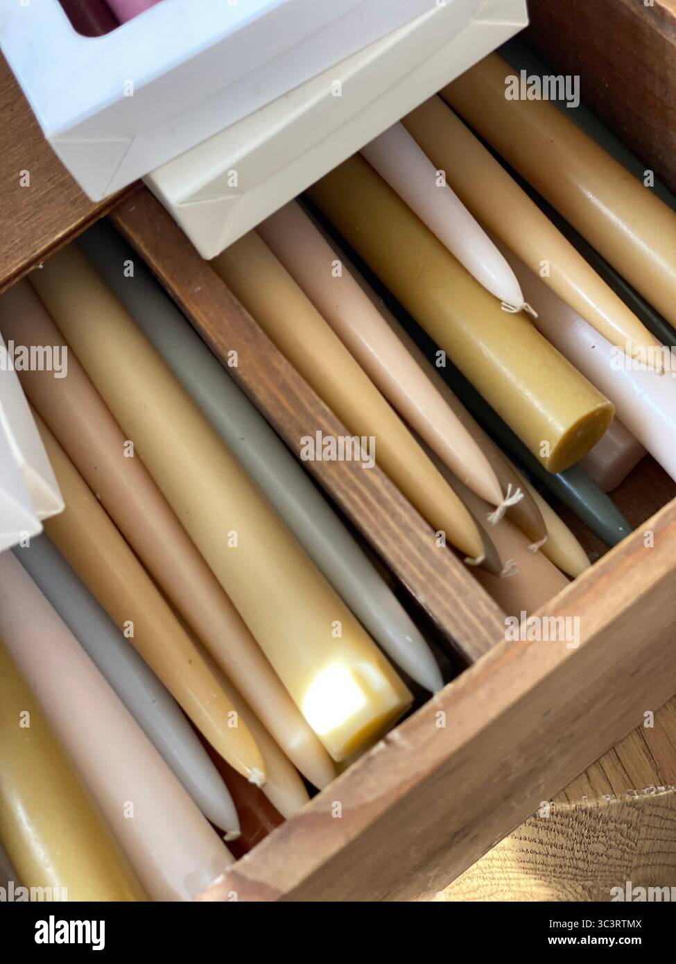 Candele di cera assortite in scatola di legno con illuminazione a soffitto, utili come sfondo accogliente. Foto mobile Foto Stock