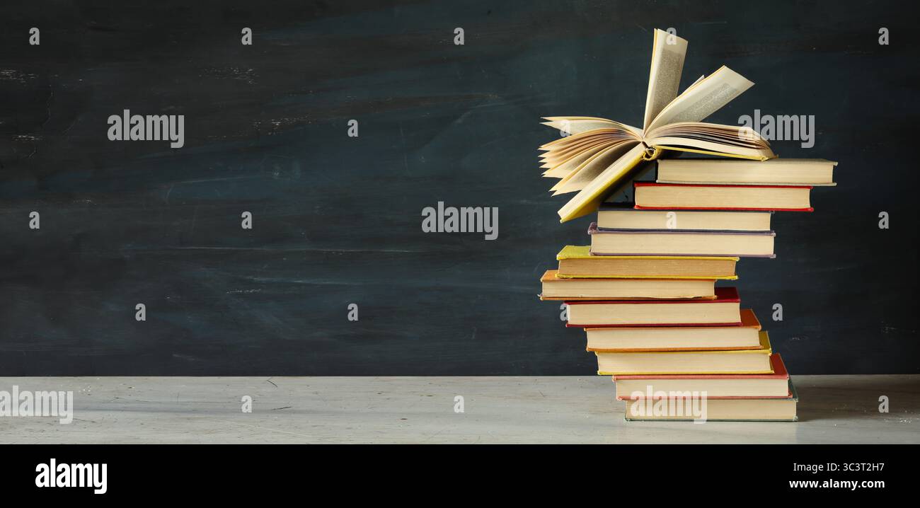 Un mucchio di libri multicolore su sfondo scuro e grungioso Foto Stock