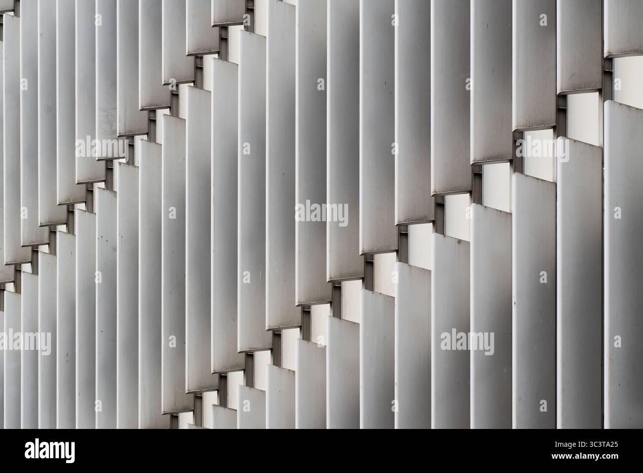 Facciata astratta dell'ufficio con alette ritmiche in metallo verticali in allineamento sfalsato Foto Stock