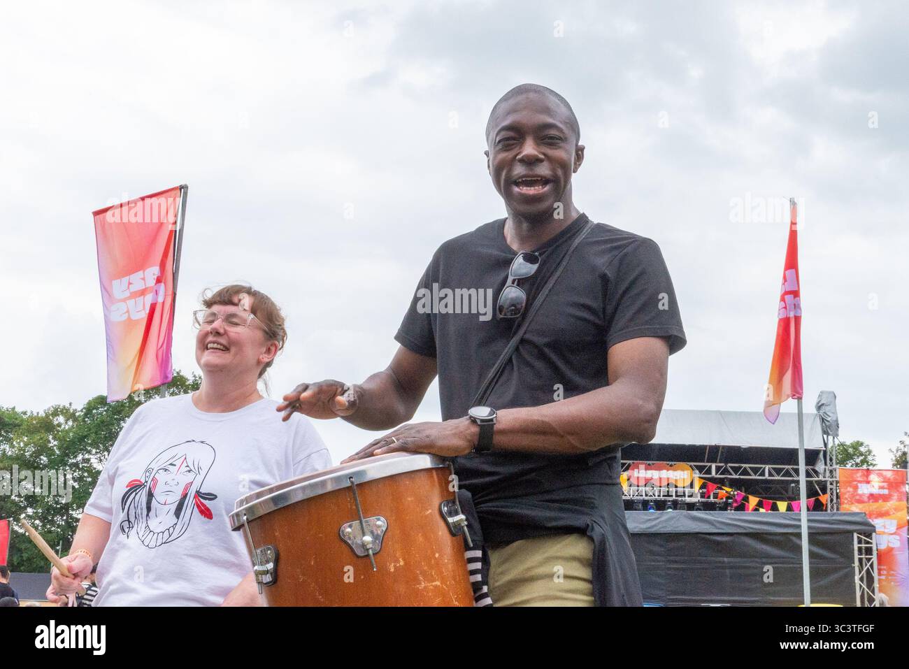 Priory Park, Southend on Sea, Essex, Regno Unito. 27 luglio 2025. Il deputato laburista per Southend East e Rochford si è offerto volontario per unirsi ai batteristi BrazilArte durante la visita al festival musicale Lazydays a Priory Park, Southend. La troupe di tamburi vagava per l'arena chiedendo casualmente ai membri del pubblico di unirsi al deputato che stava godendo del festival locale e lo ha convinto a partecipare. Autentica situazione non allestita Foto Stock