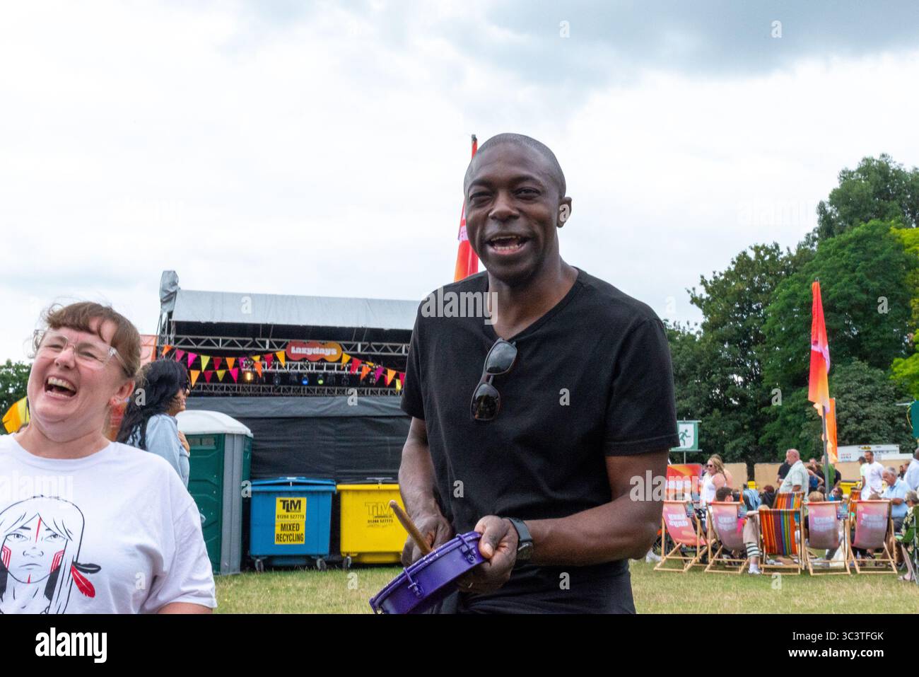 Priory Park, Southend on Sea, Essex, Regno Unito. 27 luglio 2025. Il deputato laburista per Southend East e Rochford si è offerto volontario per unirsi ai batteristi BrazilArte durante la visita al festival musicale Lazydays a Priory Park, Southend. La troupe di tamburi vagava per l'arena chiedendo casualmente ai membri del pubblico di unirsi al deputato che stava godendo del festival locale e lo ha convinto a partecipare. Autentica situazione non allestita Foto Stock