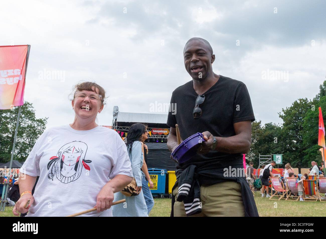 Priory Park, Southend on Sea, Essex, Regno Unito. 27 luglio 2025. Il deputato laburista per Southend East e Rochford si è offerto volontario per unirsi ai batteristi BrazilArte durante la visita al festival musicale Lazydays a Priory Park, Southend. La troupe di tamburi vagava per l'arena chiedendo casualmente ai membri del pubblico di unirsi al deputato che stava godendo del festival locale e lo ha convinto a partecipare. Autentica situazione non allestita Foto Stock