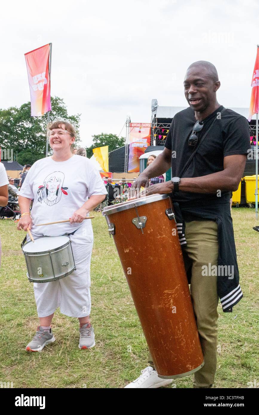 Priory Park, Southend on Sea, Essex, Regno Unito. 27 luglio 2025. Il deputato laburista per Southend East e Rochford si è offerto volontario per unirsi ai batteristi BrazilArte durante la visita al festival musicale Lazydays a Priory Park, Southend. La troupe di tamburi vagava per l'arena chiedendo casualmente ai membri del pubblico di unirsi al deputato che stava godendo del festival locale e lo ha convinto a partecipare. Autentica situazione non allestita Foto Stock