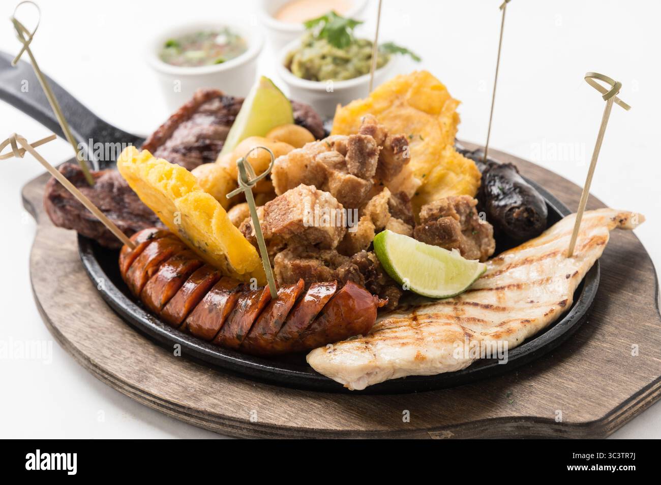 Fajitas di pollo e manzo sfrigolanti con peperoni grigliati e cipolle su padella in ghisa. Cucina messicana Tex-Mex fresca con lime e tortillas. Foto Stock