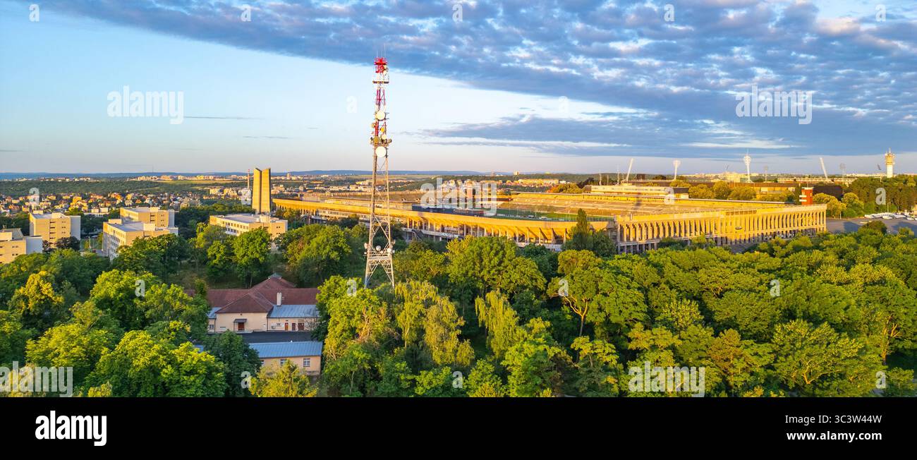 Il grande Stadio Strahov si erge di primo piano a Praga, circondato da una vegetazione lussureggiante. Questo luogo storico mette in mostra la sua architettura sullo sfondo di un vibrante cielo al tramonto, catturando l'essenza della città. Foto Stock