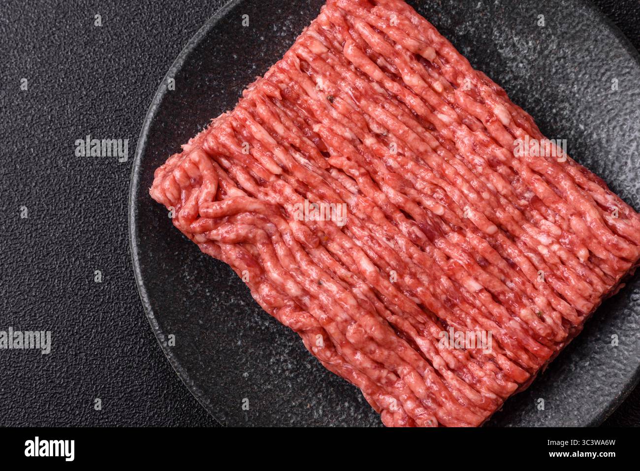 Carne di manzo macinata cruda, ingrediente per preparare cotolette o polpette. Carne cruda macinata per il vostro background Foto Stock