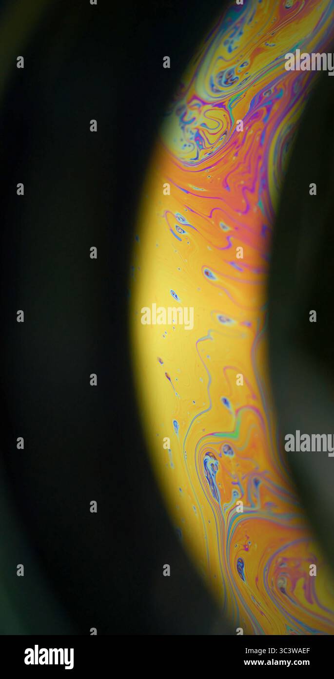 Liquido a benzina. Pittura mistica. Colorato Arch emulsione arancio giallo olio consistenza miscelazione colorante. Sfondo sfocato luminoso, spazio notturno nero. Foto Stock