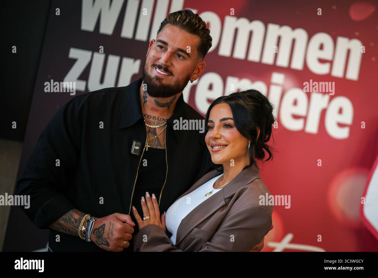 Essen, Germania. 27 luglio 2025. Le celebrità della reality TV Mike Heiter (l) e sua moglie Leyla Heiter, ex Leyla Lahouar, si trovano di fronte a un muro promozionale per il documentario sul loro matrimonio durante un servizio fotografico. Crediti: Christoph Reichwein/dpa/Alamy Live News Foto Stock