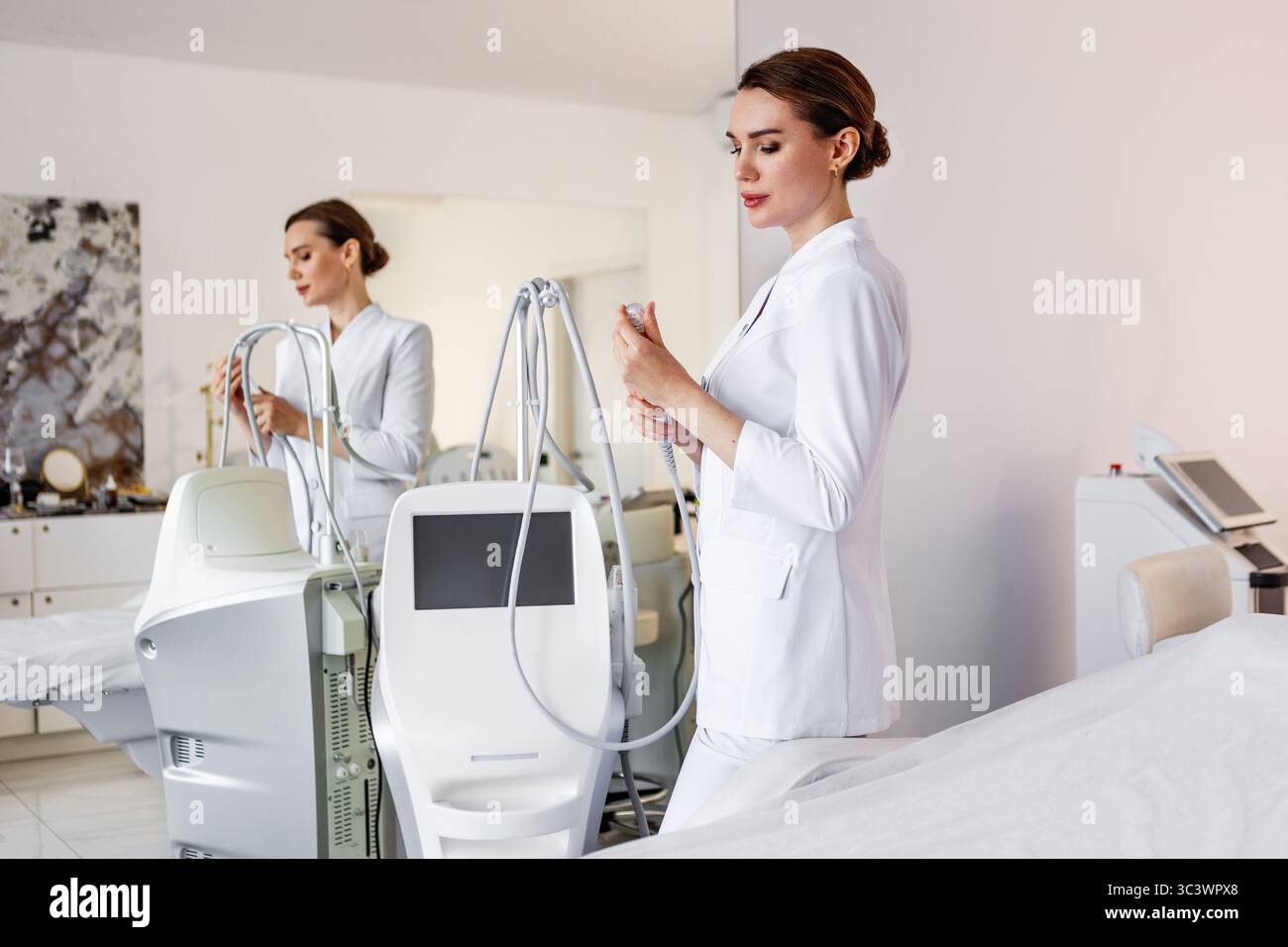 Cosmetologo professionista in uniforme bianca con moderna macchina laser estetica per il trattamento non invasivo della pelle in clinica di bellezza o spa medica, Advan Foto Stock