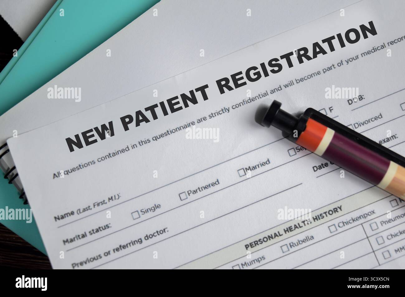 Concetto di modulo di registrazione per un nuovo paziente scrivere su un documento isolato su un tavolo in legno. Foto Stock
