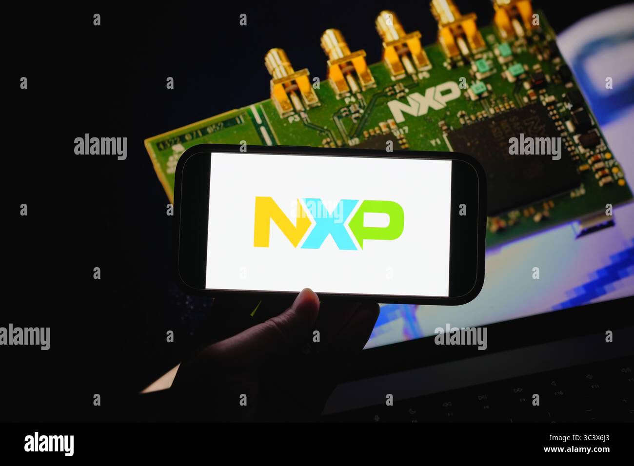 Roosendaal, Paesi Bassi – 14 luglio 2025: Uno schermo mobile che mostra il logo NXP Semiconductors con uno dei suoi chip per computer sullo sfondo. Foto Stock
