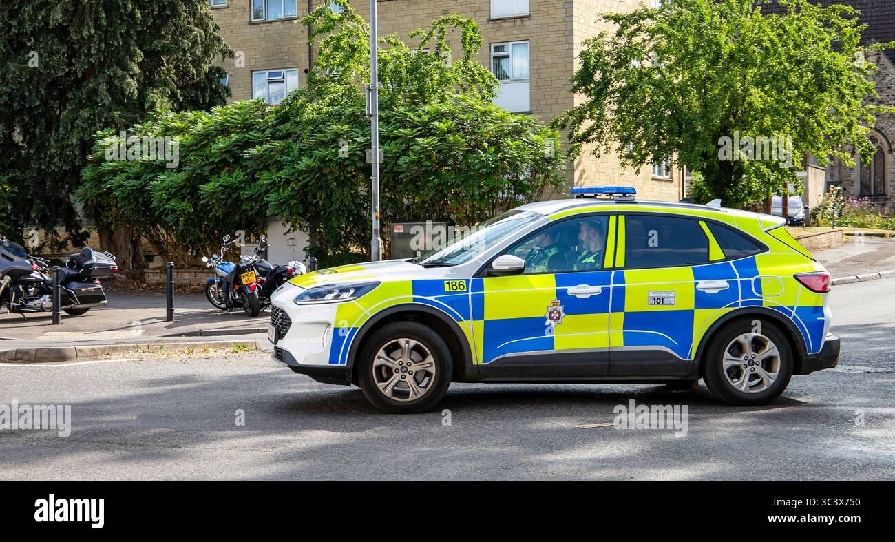 Un SUV della polizia del Wiltshire con segnaletica ad alta visibilità che guida lungo una strada suburbana a Calne Wiltshire vicino a alberi e motociclette in una giornata limpida Foto Stock