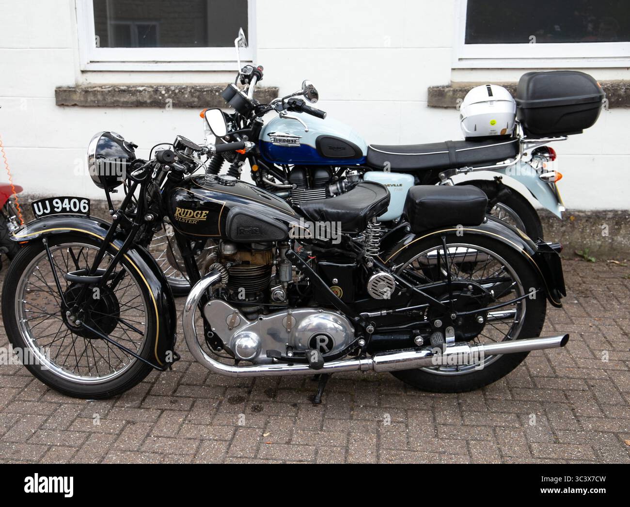 Due motociclette d'epoca classiche 1937 Rudge Ulster e Triumph Bonneville T100 parcheggiate fianco a fianco su una superficie pavimentata presso il Calne bike Meet 2025 Foto Stock