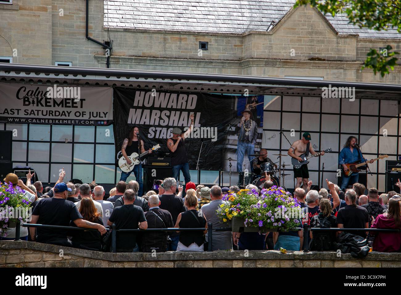 Esibizione dal vivo di gruppi rock degli Hells Bells AC/DC su un palco all'aperto durante il Calne Bike Meet con una folla di persone. Foto Stock
