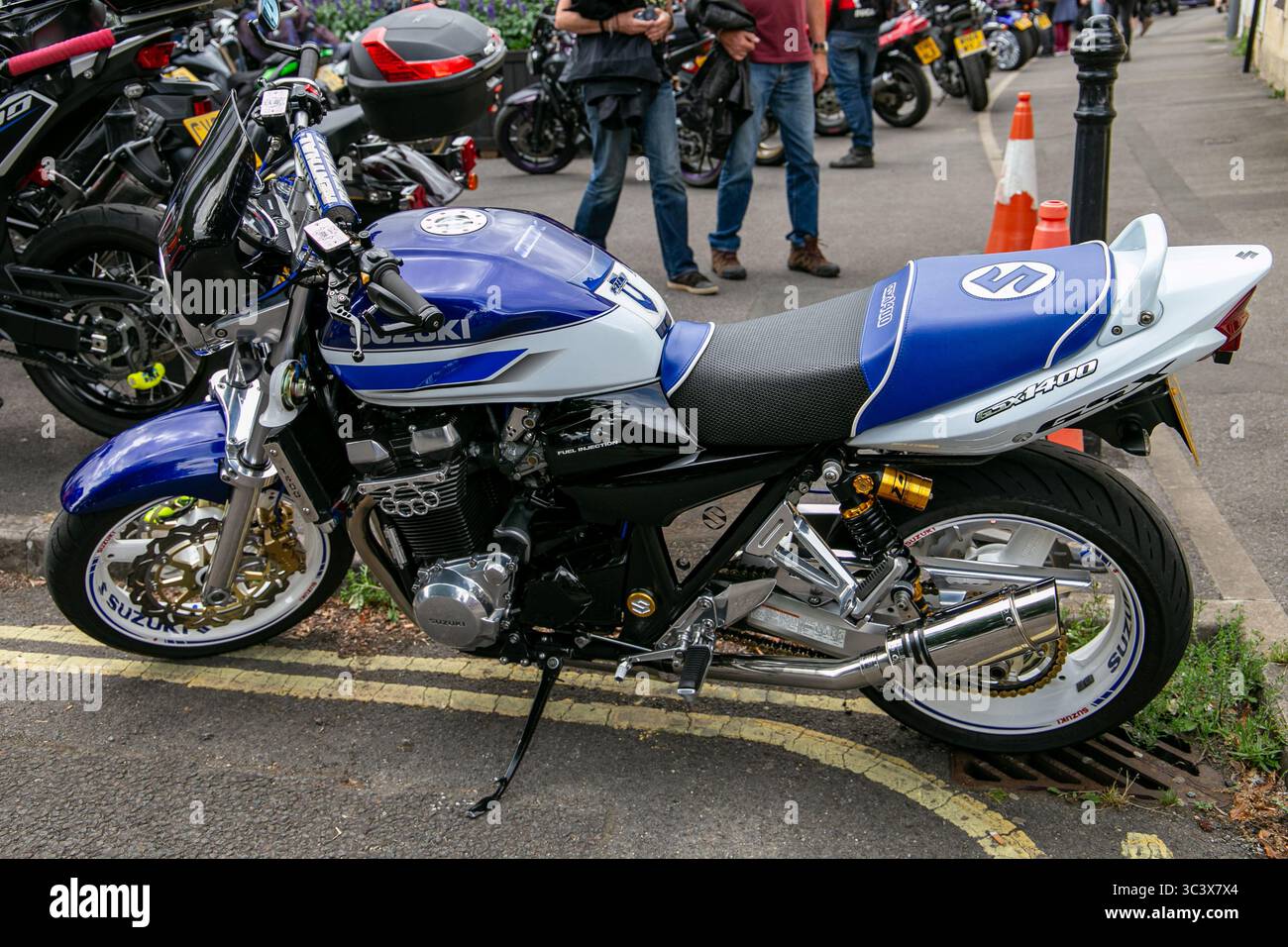 Moto Suzuki GSX 1400 blu e bianca parcheggiata all'aperto presso la moto di calne Meet 2025 con altre moto e persone sullo sfondo Foto Stock