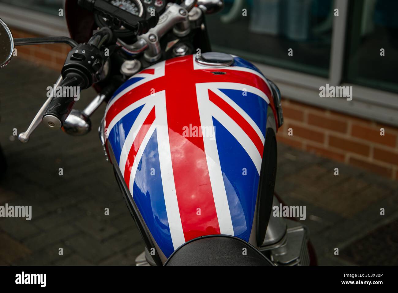 Primo piano di un serbatoio carburante/benzina per motociclette con design Union Jack, che mette in risalto l'identità e lo stile britannici in un parcheggio Foto Stock