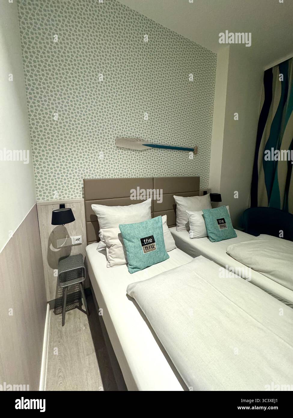 Camera moderna con letti gemelli, arredamento minimalista e cuscini d'accento presso il NIU Hotel, Germania. Foto Stock