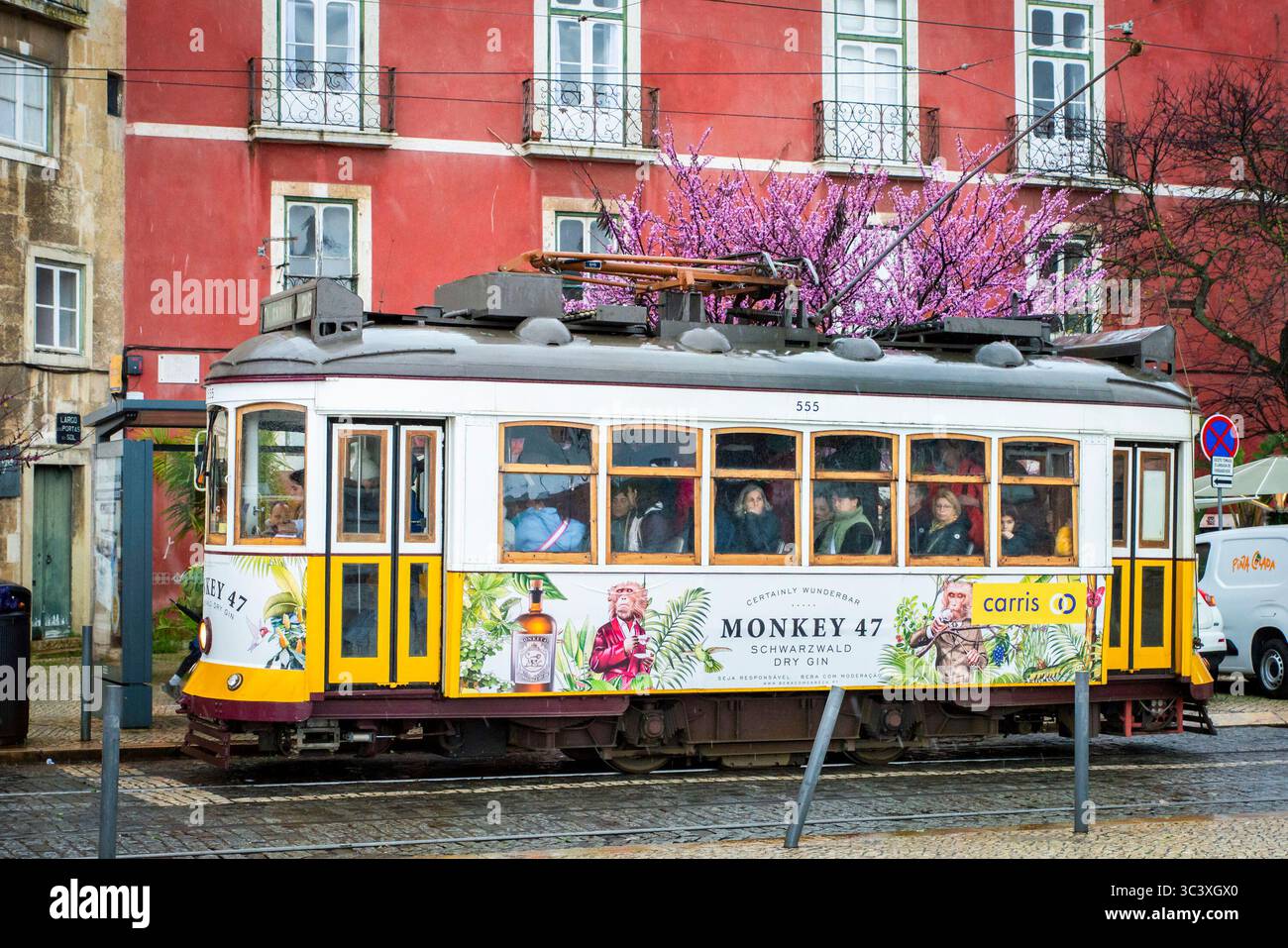 Lisbona, Portogallo, 7 marzo 2025. Vista di un colorato tram 28 di fronte a un edificio rosso nel centro di Lisbona. Foto Stock