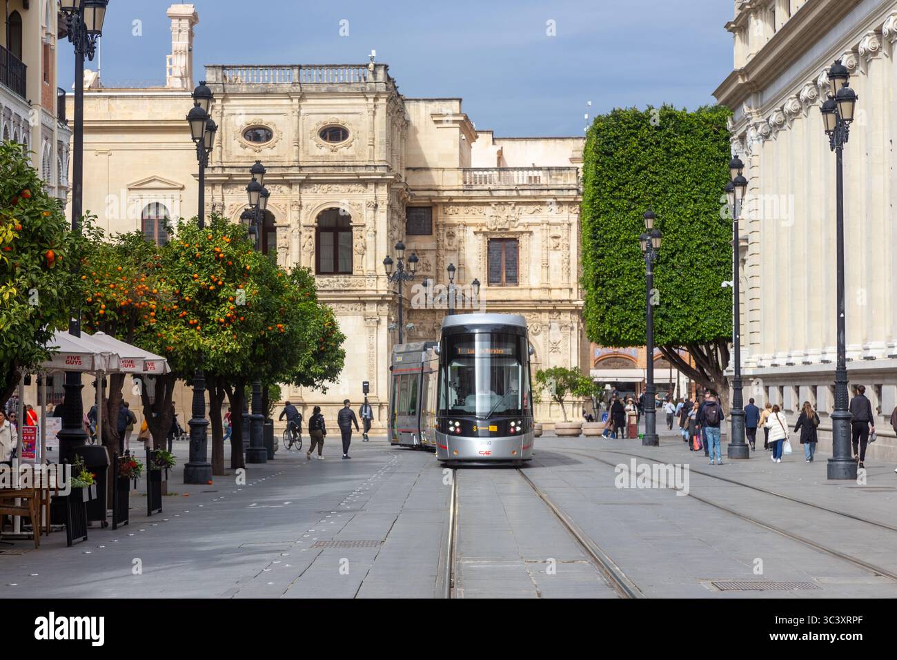 Metrocentro Seville Spain Light Transit tram Car, passeggeri a bordo. Gente che cammina nel centro città affollato via Avenida de la Constitucion vicino alla Cattedrale Foto Stock