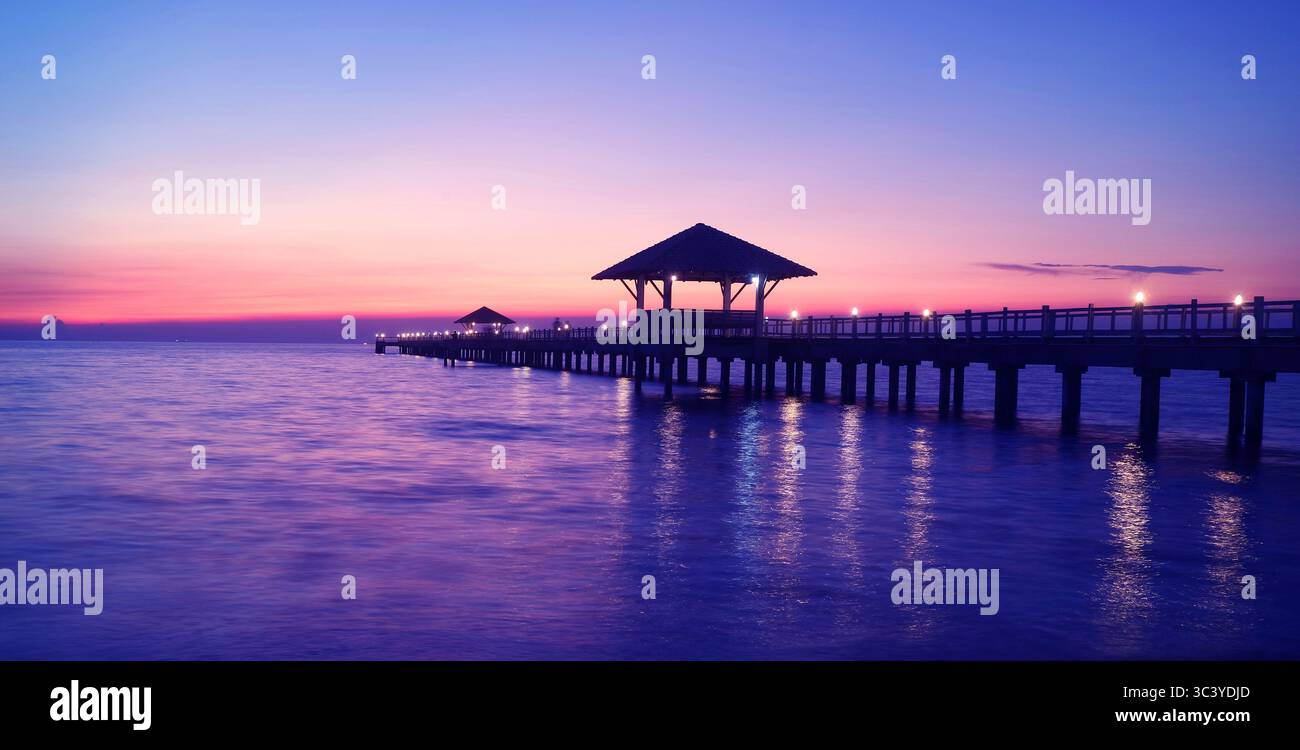 Sagoma del molo in legno con padiglione al crepuscolo nei toni del blu viola Foto Stock