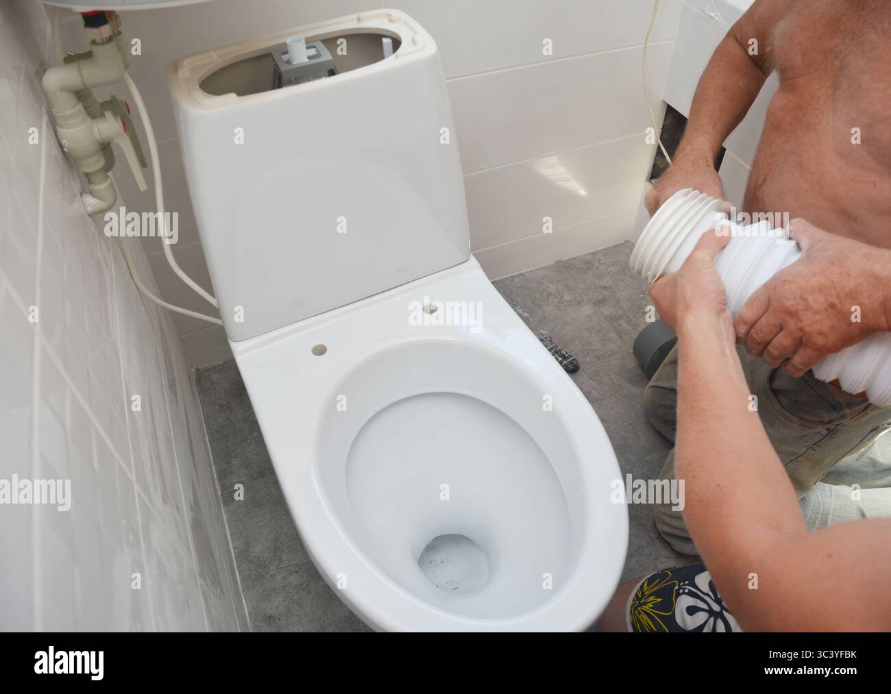 Riparatore che installa il wc a filo, la ciotola del wc nel bagno Foto Stock