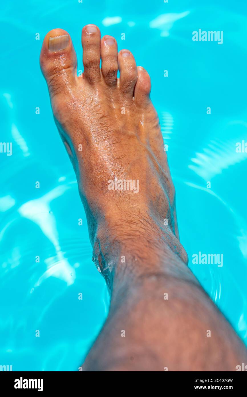 Bellissimi piedi con 30 centimetri di bianco uomo caucasico all'interno di acqua blu e piscina Foto Stock