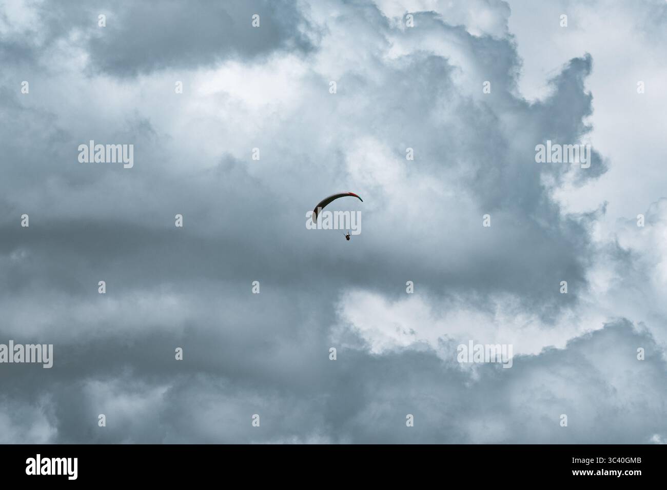 Vista di un parapendio che si libra sullo sfondo di spettacolari nuvole di tempesta a Ortisei, Trentino-alto Adige, Italia. Foto Stock
