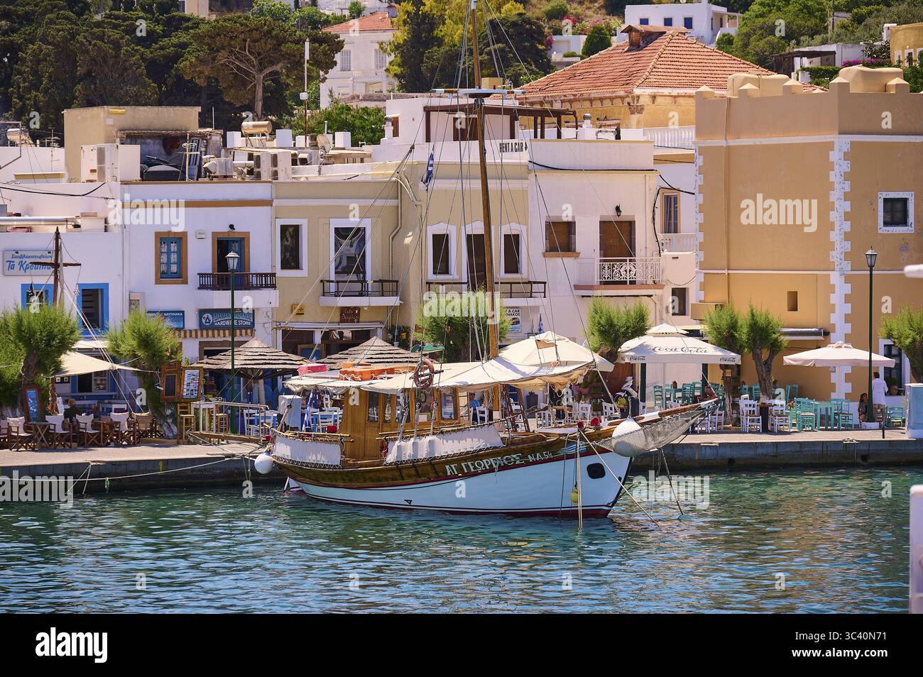 Barca tradizionale in legno in un vivace porto con ristoranti adiacenti, Lakki, Leros, Dodecaneso, isole greche, Grecia Foto Stock