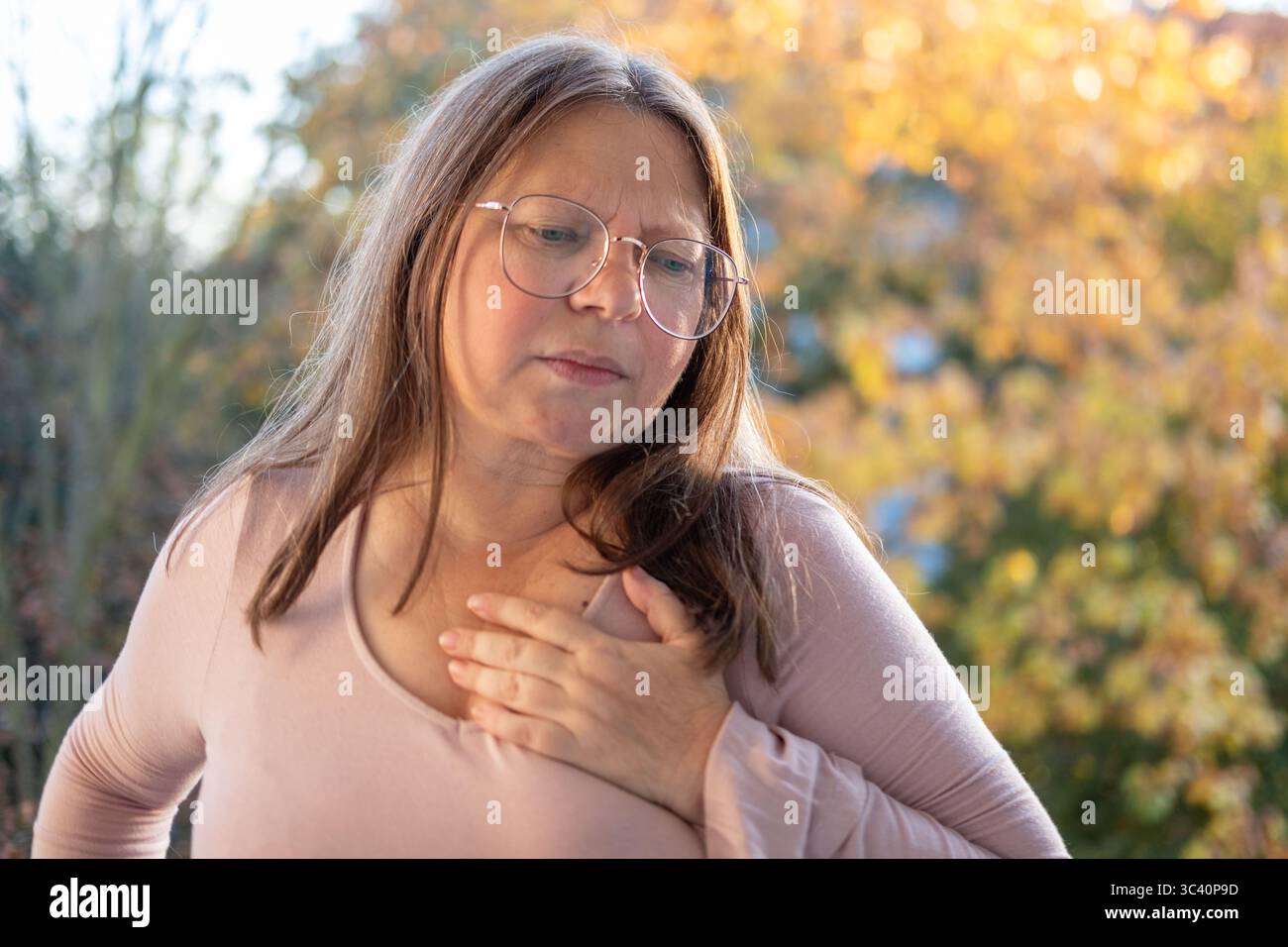 Donna di mezza età che soffre di dolore toracico, che preme le mani verso il cuore. Concetto di problemi di salute, arresto cardiaco, e angoscia, rischio di salute, insufficienza cardiaca Foto Stock