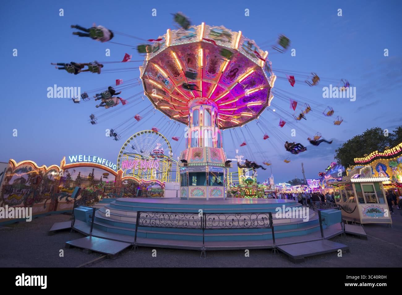 Il carosello luminoso accende una fiera colorata, una giostra a catena, la festa primaverile, Cannstatter Wellenflug, illuminata, ora blu, Cannstatter Wasen, Ba Foto Stock