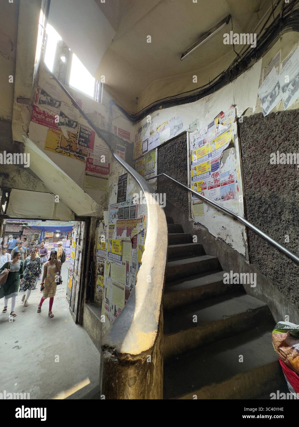 Una stretta scala coperta da poster con luce diretta dall'alto, Indian Coffee House, College Street, Kolkata, West Bengal, India Foto Stock