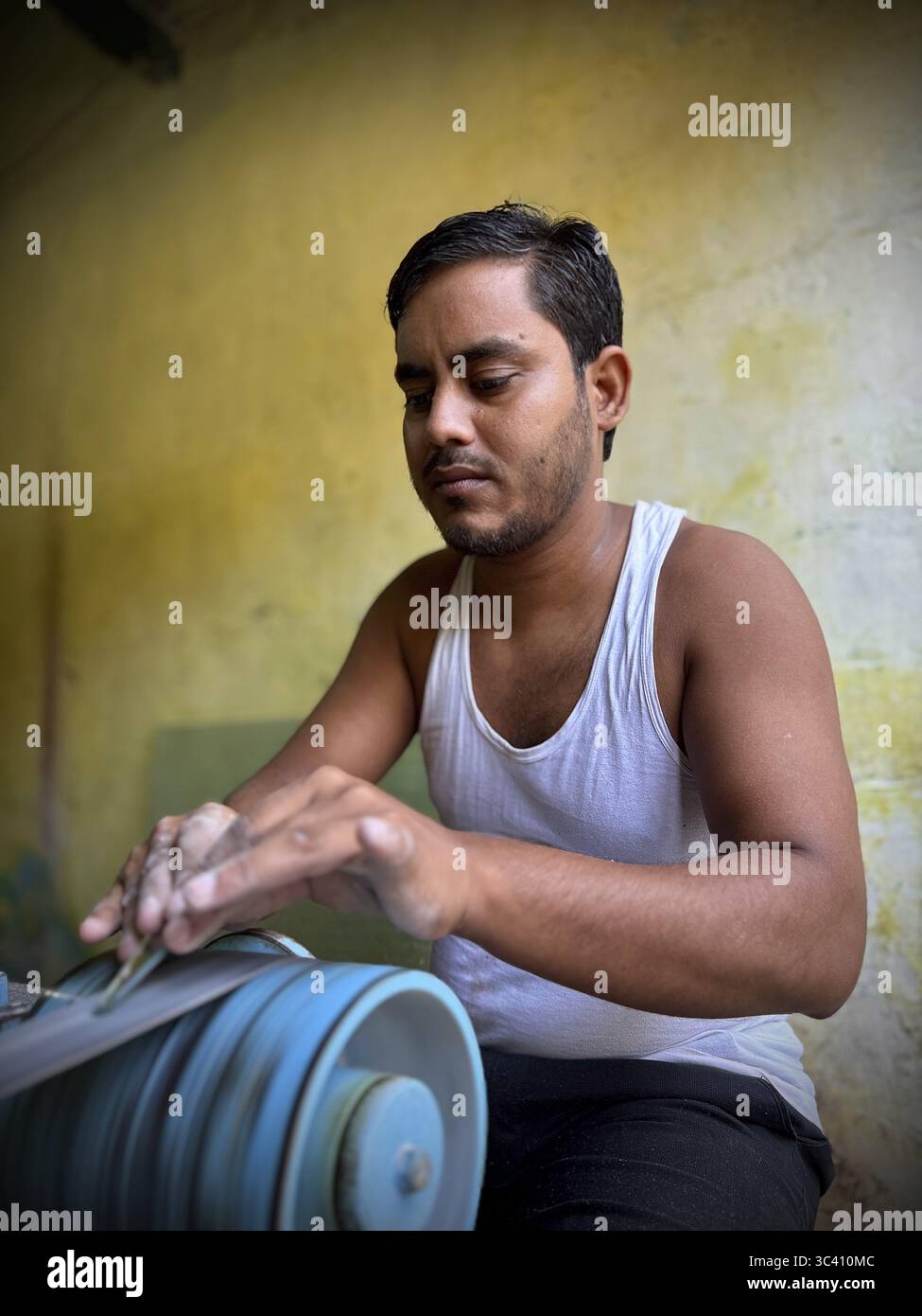 Un uomo lavora intensamente con una mola su una macchina, Kolkata, Bengala Occidentale, India Foto Stock