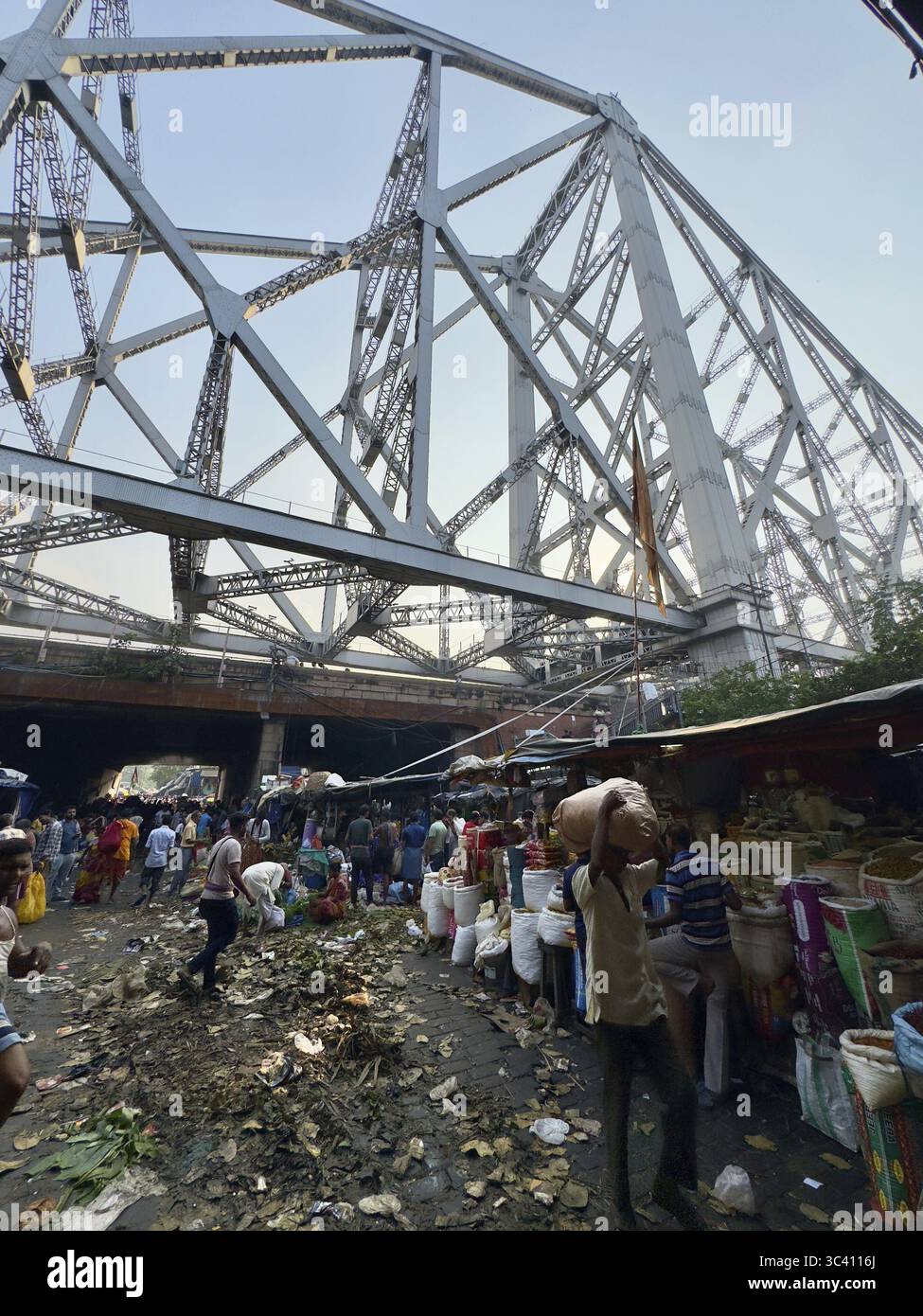 Mercato sotto un grande ponte pieno di gente e spazzatura sparsa a terra, Kolkata, Bengala Occidentale, India Foto Stock